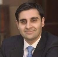 Headshot of a person wearing a suit and tie, smiling.